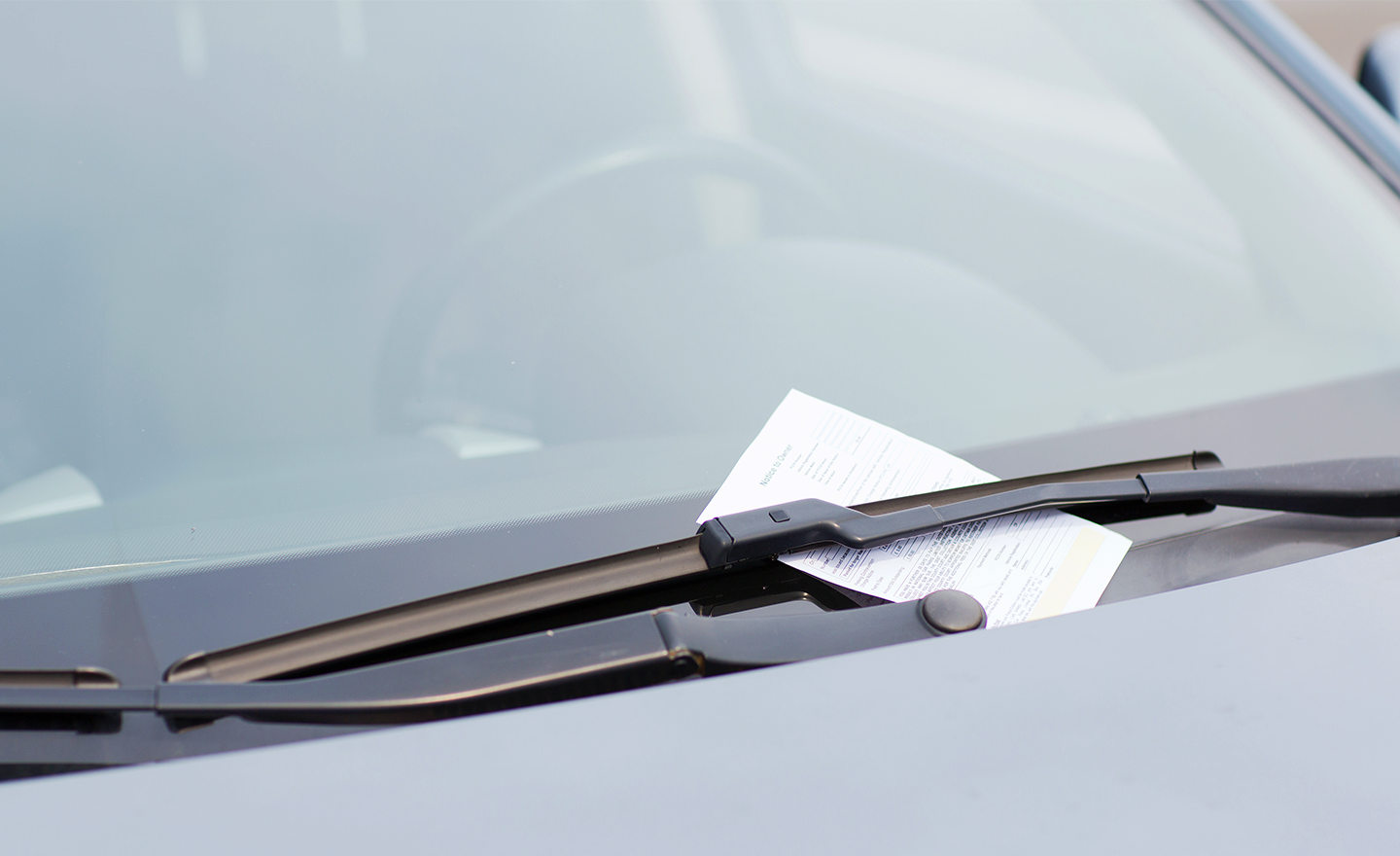 Parking ticket is placed under windshield wipers of vehicle