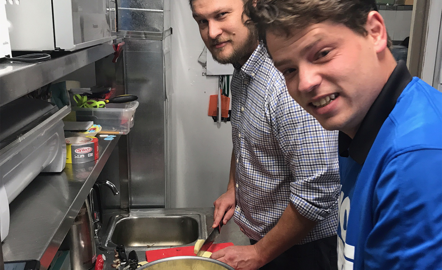 Two volunteers, one in a blue Western Financial Group volunteer shirt, peel and chop potatoes during a volunteer shift at Streets Alive in Lethbridge