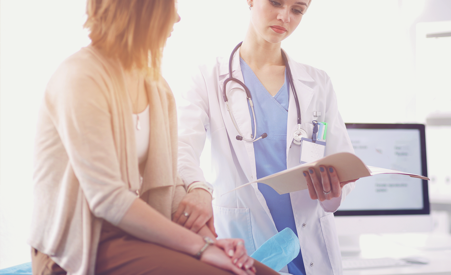 Female doctor goes over medical information in doctor's office with female patient