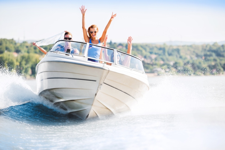 Young adults driving a boat, having fun on a lake