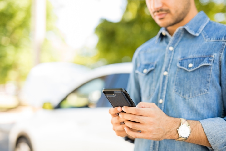 Man uses his cellphone to call road side assistance.