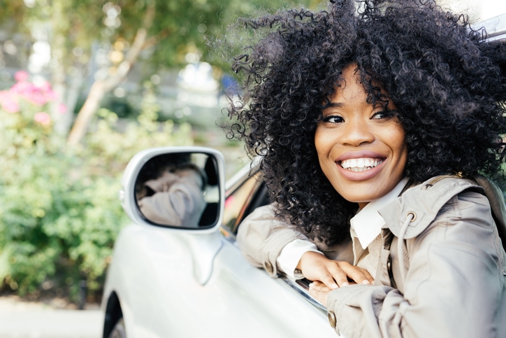 Young woman leans out of her car window