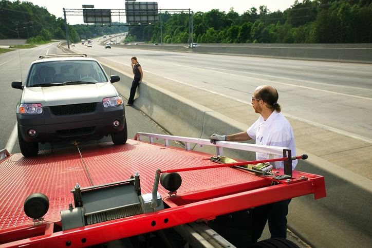 Man towing a women's car off of a freeway