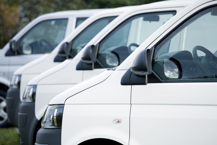 Four white work vans parked in a row