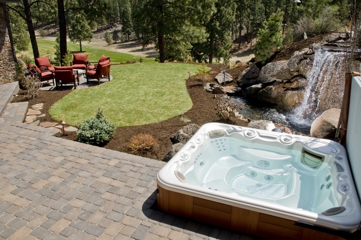 Newly landscaped and renovated backyard with a hot tub and waterfall feature