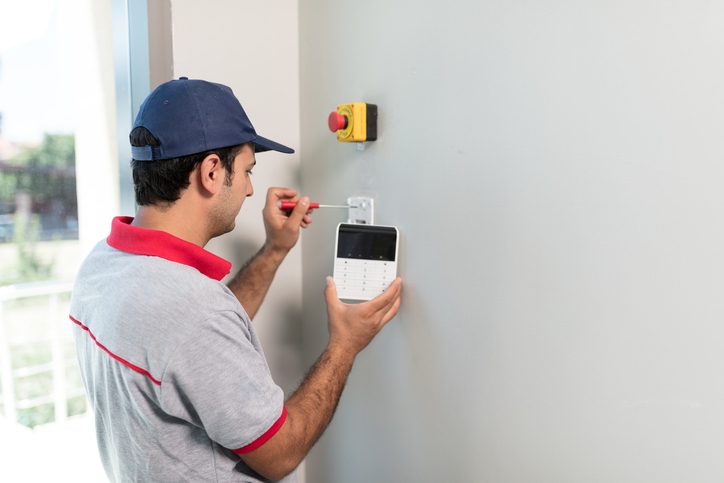 Man installs security system control panel on to home's wall.