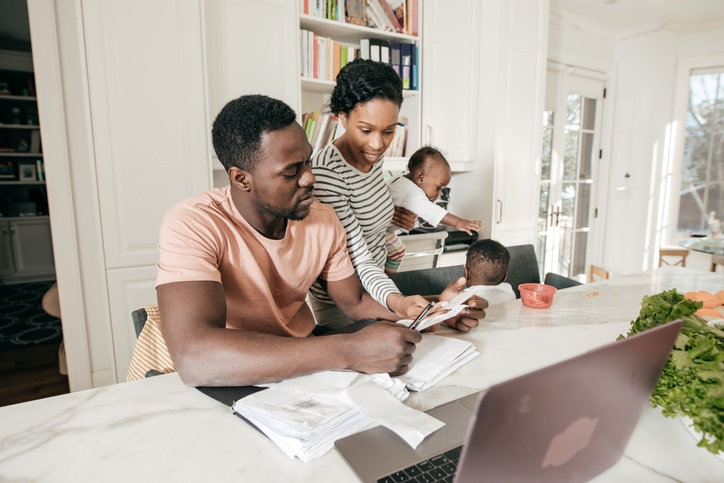 Young family sits in their kitchen making an inventory list for home insurance