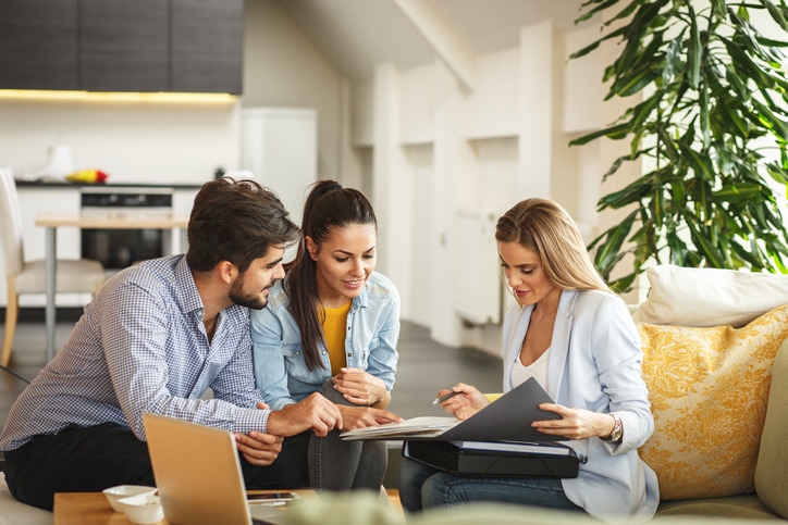 Young couple sitting with an Insurance Adviser going over their home insurance policy