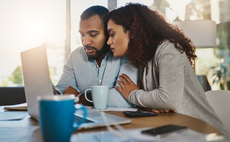 A young couple reviews life insurance policies on a laptop.