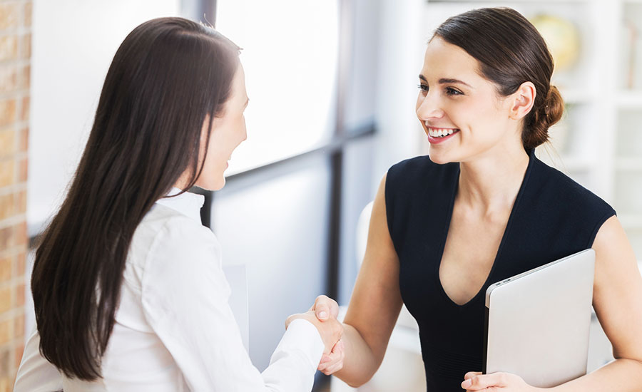 Confident woman shakes hands with another woman in a business setting