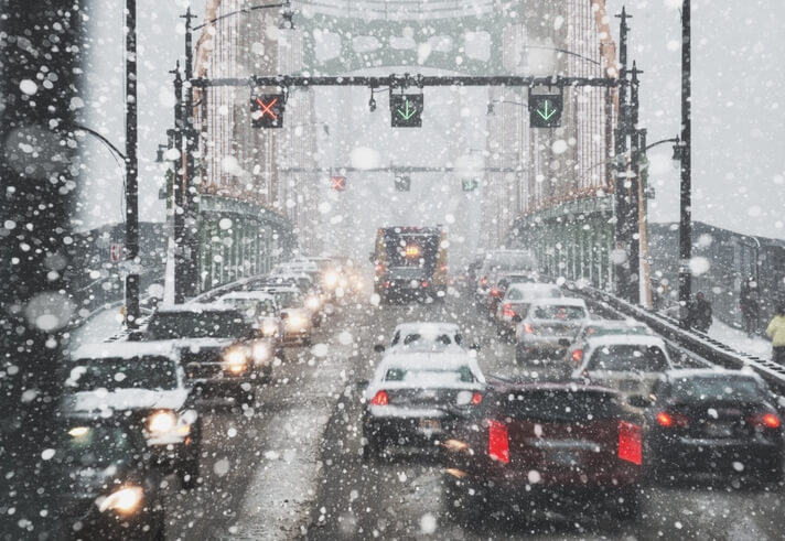 Cars driving across a bridge in a snow storm