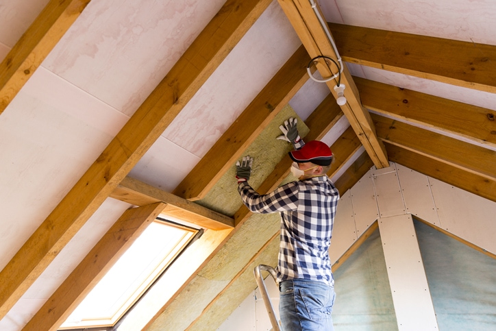 Man installing thermal roof insulation layer - using mineral wool panels. Attic renovation and insulation concept